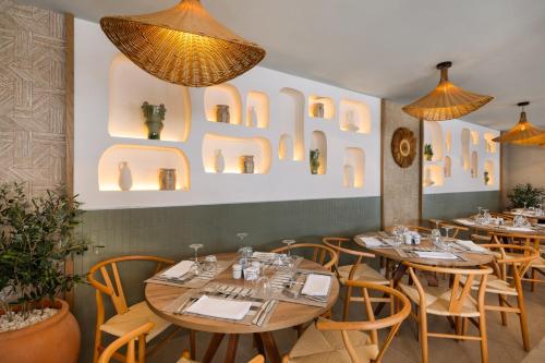 a restaurant with wooden tables and chairs and lights at Hotel Riu Palace La Mola in Playa Migjorn