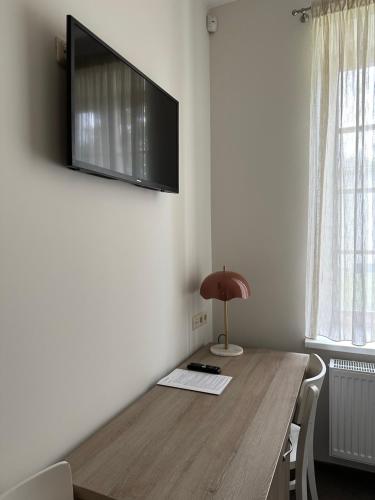 a room with a wooden table with a television on the wall at Birštono Banginukas poilsio namai in Birštonas