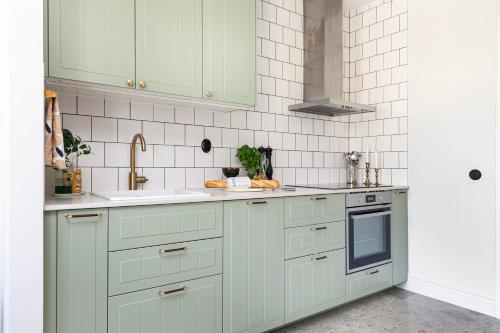a kitchen with white cabinets and a sink at NEW Stylish Coastal Retreat, 1 Min to the Ocean in Lerberget