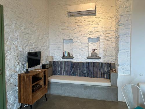 a room with a tv and a stone wall at Serenity Hill in Kithnos