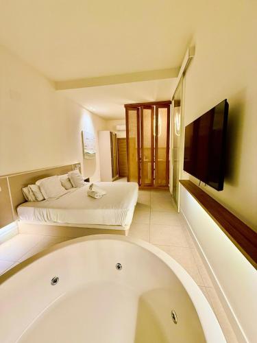 a bathroom with a tub and a bed and a television at Reina Victoria Velázquez in Alicante
