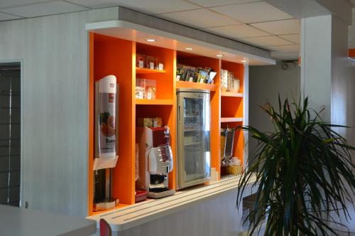um expositor laranja com uma máquina de café em Premiere Classe Bordeaux Sud Villenave D'ornon em Villenave-dʼOrnon