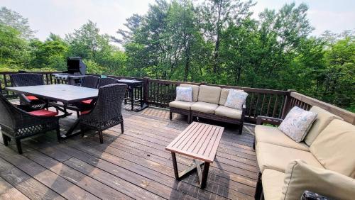 a deck with furniture and a table and chairs at The Nest at Pinecrest by AvantStay Spacious Deck Game Room Fire Pit in Pocono Pines