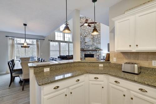 a kitchen with white cabinets and a living room at The Nest at Pinecrest by AvantStay Spacious Deck Game Room Fire Pit in Pocono Pines