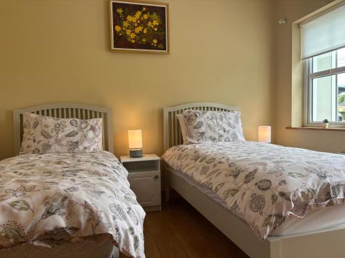 a bedroom with two beds and a window and two lamps at Albert Lock Bungalow in Carrick on Shannon