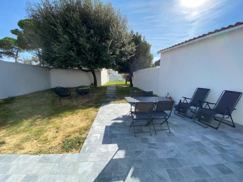 ル・ボワ・プラージュ・アン・レにあるMaison Les Tamarisのパティオ(椅子、テーブル、フェンス付)