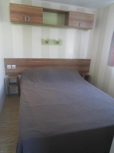 une chambre avec un lit avec une tête de lit en bois dans l'établissement Mobil-home, à Saint-Pierre-dʼOléron