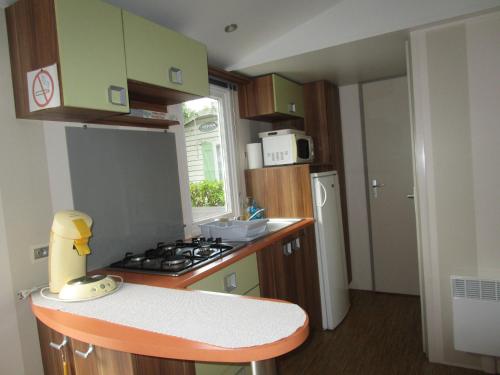 une cuisine avec une cuisinière et un comptoir dans l'établissement Mobil-home, à Saint-Pierre-dʼOléron