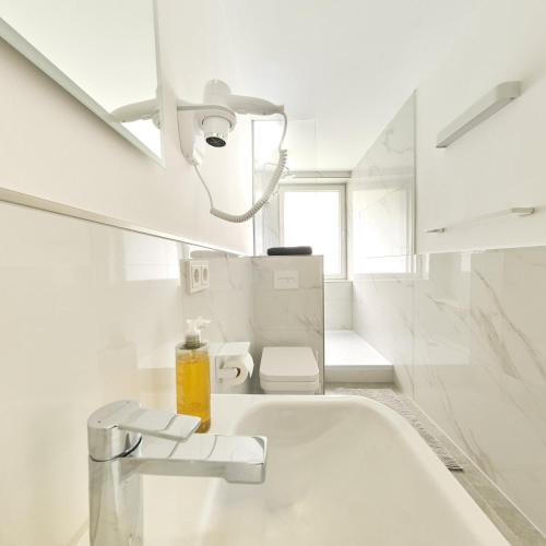 a white bathroom with a sink and a toilet at Pension Am Sültebrunnen in Bad Oeynhausen