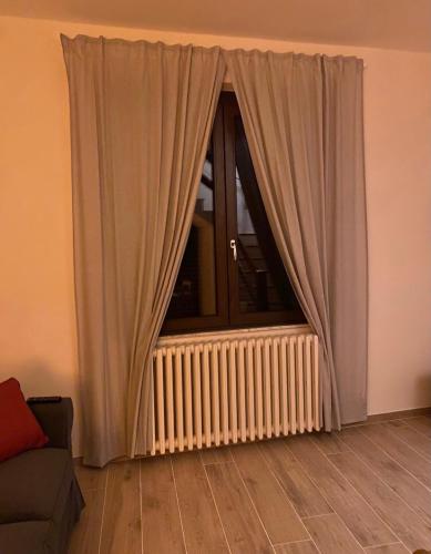 a window with curtains in a living room with a couch at Civico 1 in Cetona