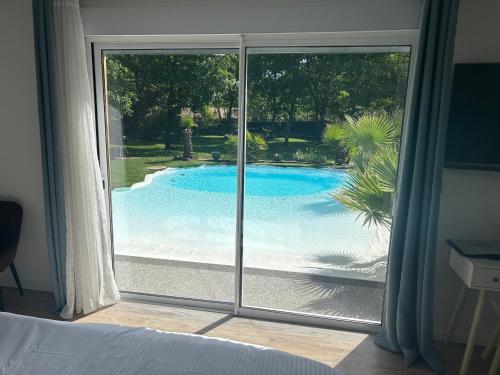 a view of a swimming pool through a window at Little Paradise in Belin-Beliet