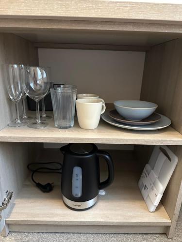 a coffee maker on a shelf with plates and glasses at Birštono Banginukas poilsio namai in Birštonas