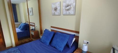 a bedroom with a bed with blue pillows and a mirror at Piso Altos de Foz in Foz