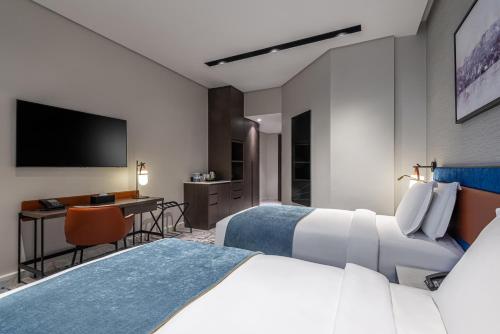 a hotel room with two beds and a desk at Durrat Jalmouda Hotel in Al Jubail