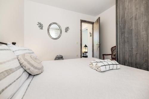 a white bedroom with a large white bed and a mirror at Arazzo Apartments in Vasilikos