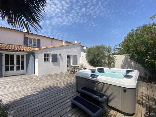 Un jacuzzi situado en una terraza de madera en Villa du Puits Cache, en Le Bois-Plage-en-Ré