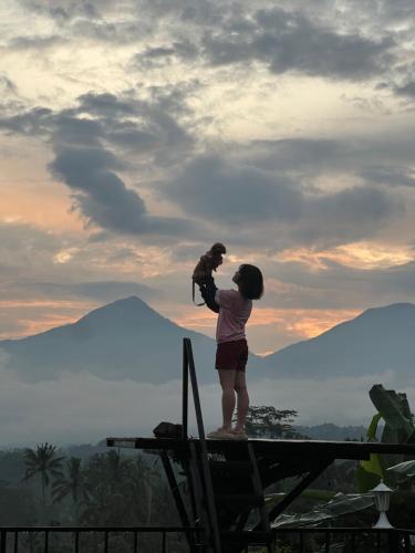 a woman holding a baby looking at the mountains at KA MANIcamp in Angsri