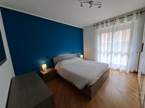 a blue bedroom with a bed and a blue wall at BG House - appartamento con giardino e garage privato in Cuneo