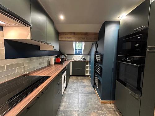 une cuisine avec des placards gris et des appareils noirs dans l'établissement GRAVACHES 3 Appt 6 pers, centre, pistes, à La Clusaz