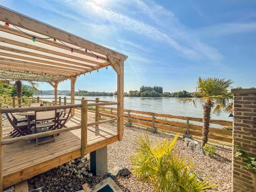 a wooden deck with a table and chairs next to the water at Eco lodge, vue exceptionnelle! in Duclair