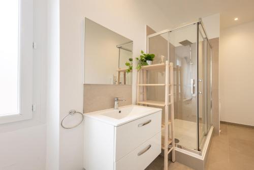 une salle de bain blanche avec un lavabo et une douche dans l'établissement Appartement 2 pièces proche de Monaco, à Beausoleil