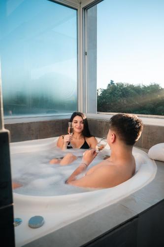 a man and woman sitting in a bathtub drinking wine at Armonium Airport in Ezeiza