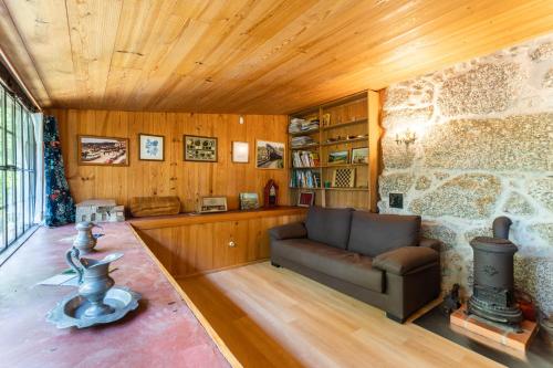 a living room with a couch and a stone wall at Chalé da Quinta "Lavoura da Bouça - Fruta Bio" in Celorico de Basto