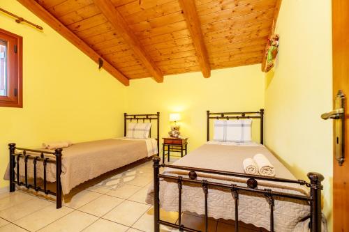 two beds in a bedroom with a wooden ceiling at Arazzo Apartments in Vasilikos