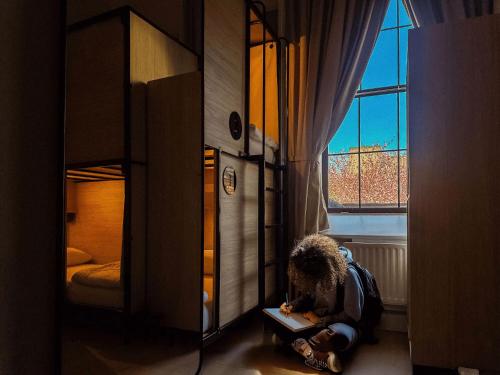 a child sitting on the floor in a bedroom with a book at Gardiner House Hostel in Dublin
