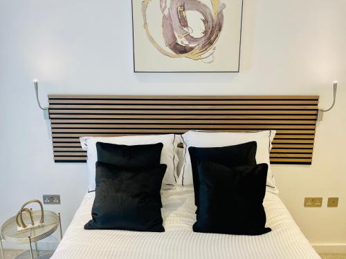 a bed with black and white pillows in a bedroom at Extra large spacious 1 Bedroom private apartment, Nr St Albans City Station, Business, contractor, Parking, WiFi in St. Albans