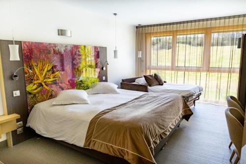 a bedroom with two beds and a painting on the wall at Hôtel L'Etang du Moulin By Céline in Bonnétage