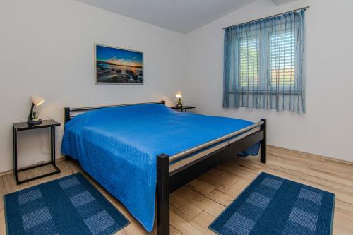 a bedroom with a blue bed and a window at Apartmani Sanja in Vir