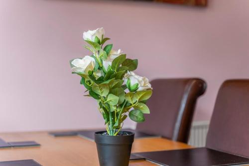 a black vase with white flowers on a table at Modern 4-Bed Serviced Apartment- Free Parking Wi-Fi - Near CBS Arena -M6 -UHCW in Exhall