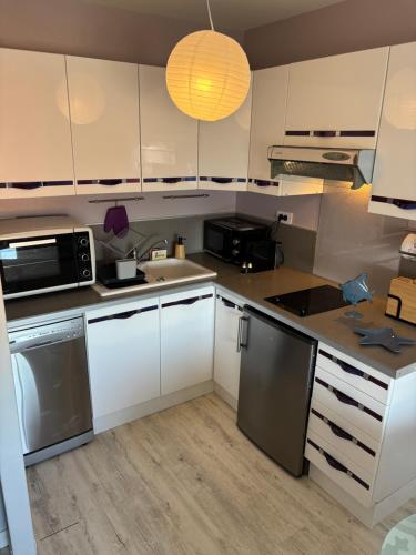 une cuisine avec des armoires blanches et des appareils en acier inoxydable dans l'établissement Mes Ptits Apparts, à La Cotinière