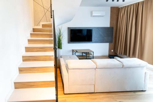 a living room with white furniture and a staircase at Czarna Perła Hel in Hel