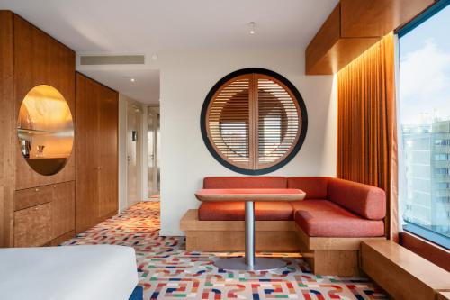 a living room with a red couch and a round mirror at The Standard, Brussels in Brussels