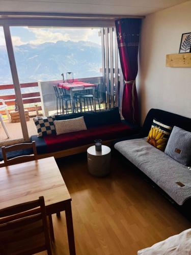 a living room with a large window with a table at Studio chaleureux, confortable, avec vue sur les Alpes 2- 3 pers in Anzère