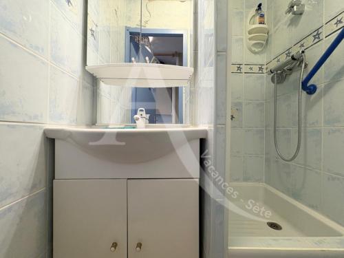 une salle de bain blanche avec un lavabo et une douche dans l'établissement Studio cabine avec vue mer et parking, à Sète