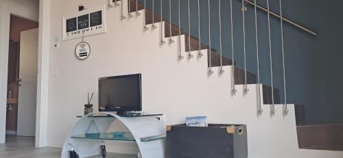 a living room with a desk with a tv and a staircase at homeliday ACTIVE in Caldana