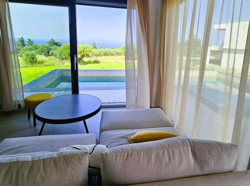 a living room with a couch and a table and a large window at Bellerive Villas in Kriopigi