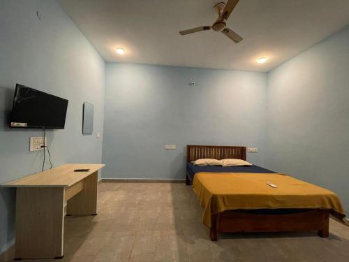 a bedroom with a bed and a desk and a ceiling fan at Eden De Pondy in Puducherry