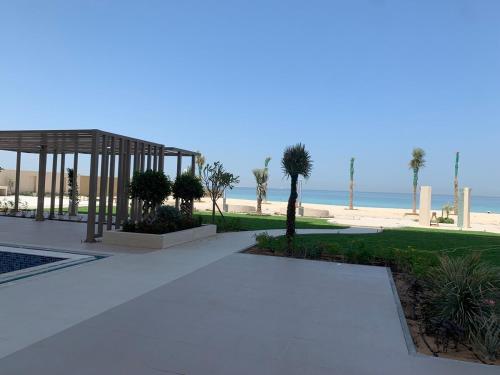 a view of the beach with a pavilion and palm trees at Luxe Private Beach Apartment Residence in Sharjah