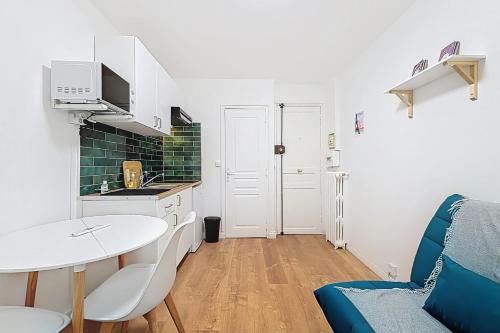une petite cuisine avec une table blanche, une table et des chaises dans l'établissement Cosy studio near Montparnasse, à Paris