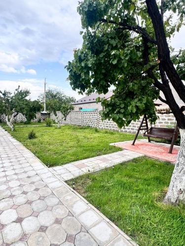 a park with a bench and a tree and grass at Hovakimyans Hotel And Pool EVN in Pʼarakʼar