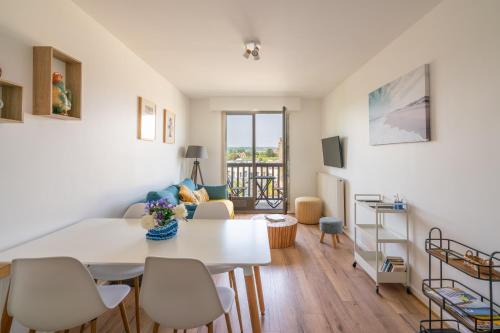un salon avec une table et des chaises blanches dans l'établissement Bleu d'Ornano - proche de la plage, à Blonville-sur-Mer
