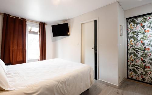 a bedroom with a white bed and a television at Auberge Val Moureze Hôtel & Spa in Mourèze