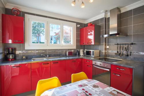 une cuisine avec des placards rouges et une table avec des chaises jaunes dans l'établissement Au printemps Japonais, à Pierre-Châtel