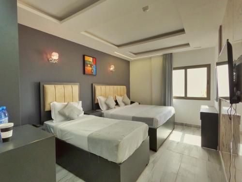 una camera d'albergo con due letti e una televisione di Holiday Season Hotel ad Aqaba
