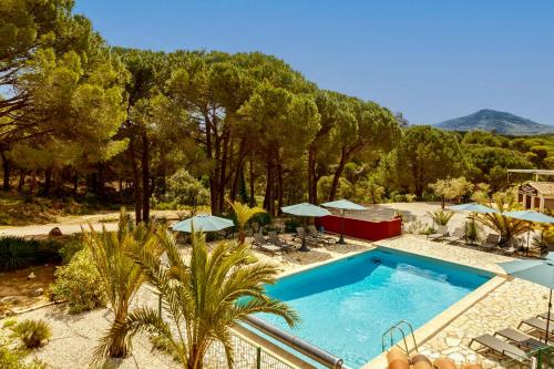 a swimming pool with chairs and umbrellas and trees at Auberge Val Moureze Hôtel & Spa in Mourèze