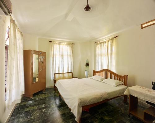 a bedroom with two beds and two windows at Ushas Homestay in Trivandrum